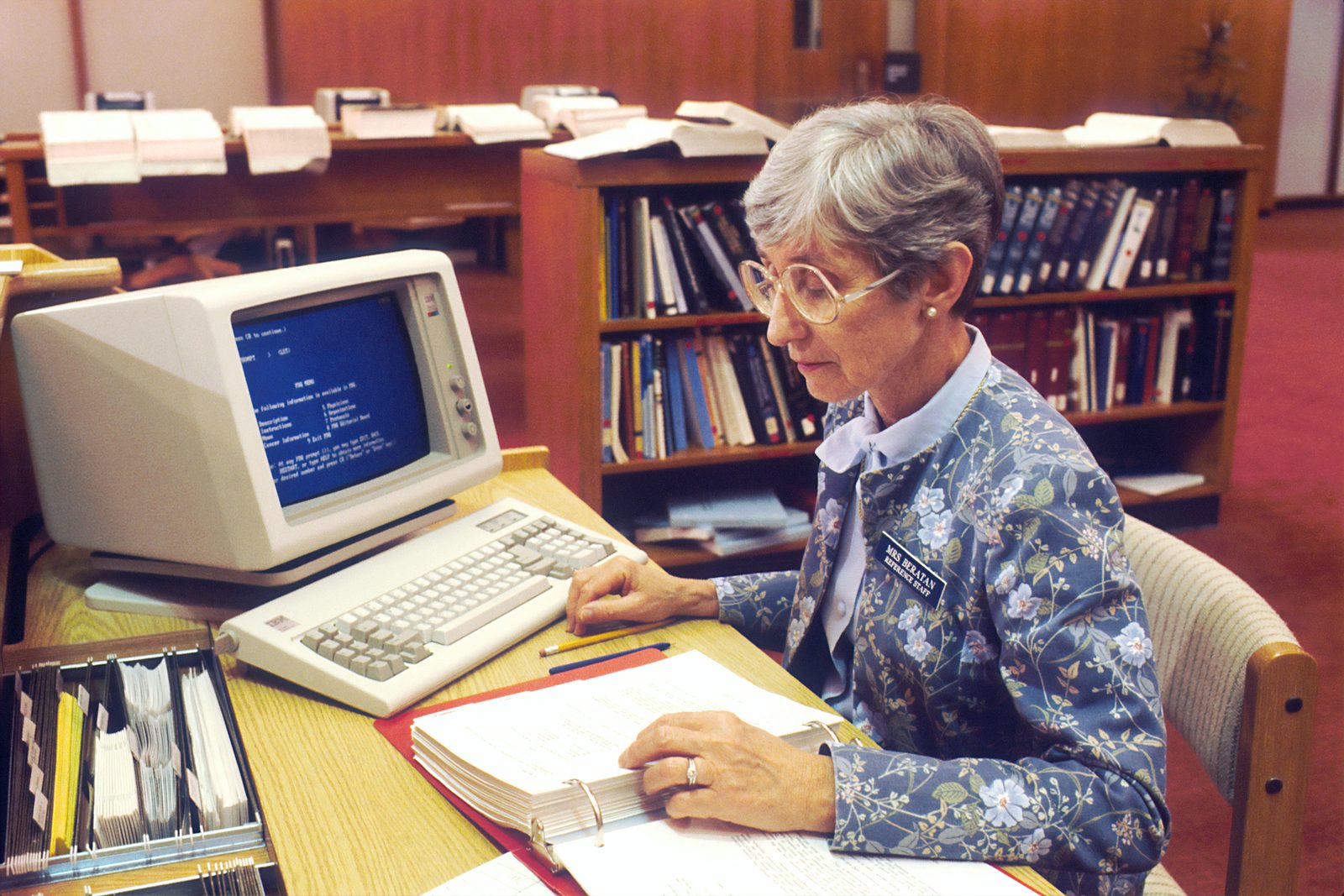 A reference clerk at an early computer terminal, decades ago